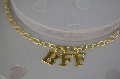 Model wears Necklace chain with and letters. Crafted with a 5.5mm link size chain in gold vermeil with serif letters spelling out  BFF (Best Friends Forever). Each letter is a classic serif uppercase font.