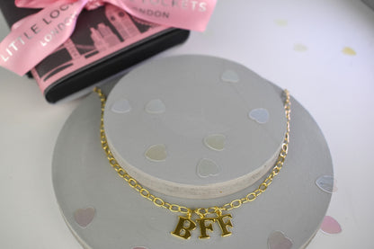 Model wears Necklace chain with and letters. Crafted with a 5.5mm link size chain in gold vermeil with serif letters spelling out  BFF (Best Friends Forever). Each letter is a classic serif uppercase font.