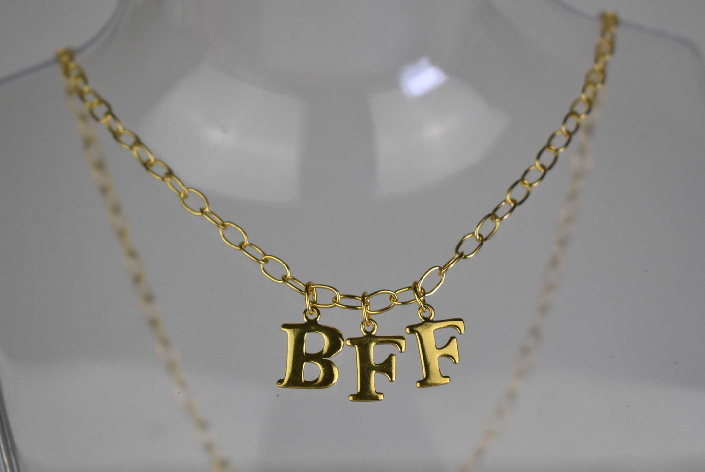 Model wears Necklace chain with and letters. Crafted with a 5.5mm link size chain in gold vermeil with serif letters spelling out  BFF (Best Friends Forever). Each letter is a classic serif uppercase font.