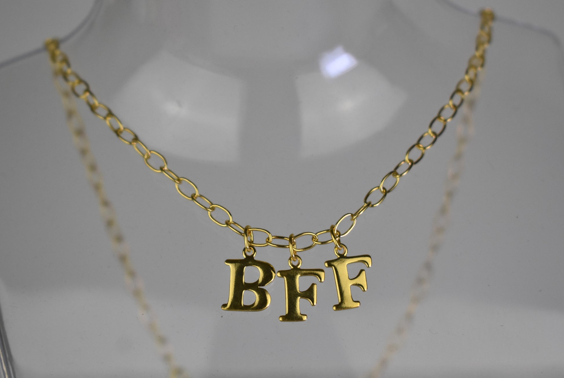 Model wears Necklace chain with and letters. Crafted with a 5.5mm link size chain in gold vermeil with serif letters spelling out  BFF (Best Friends Forever). Each letter is a classic serif uppercase font.