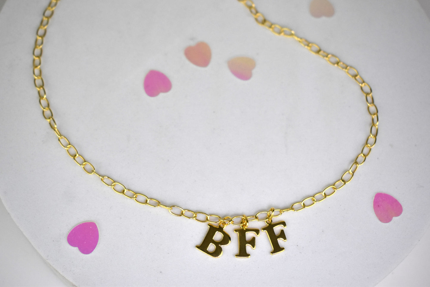Model wears Necklace chain with and letters. Crafted with a 5.5mm link size chain in gold vermeil with serif letters spelling out  BFF (Best Friends Forever). Each letter is a classic serif uppercase font.