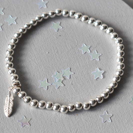 Beaded bracelet consisting of 4mm sterling silver beads  threaded on strong elastic from which is suspened a sterling silver feather charm