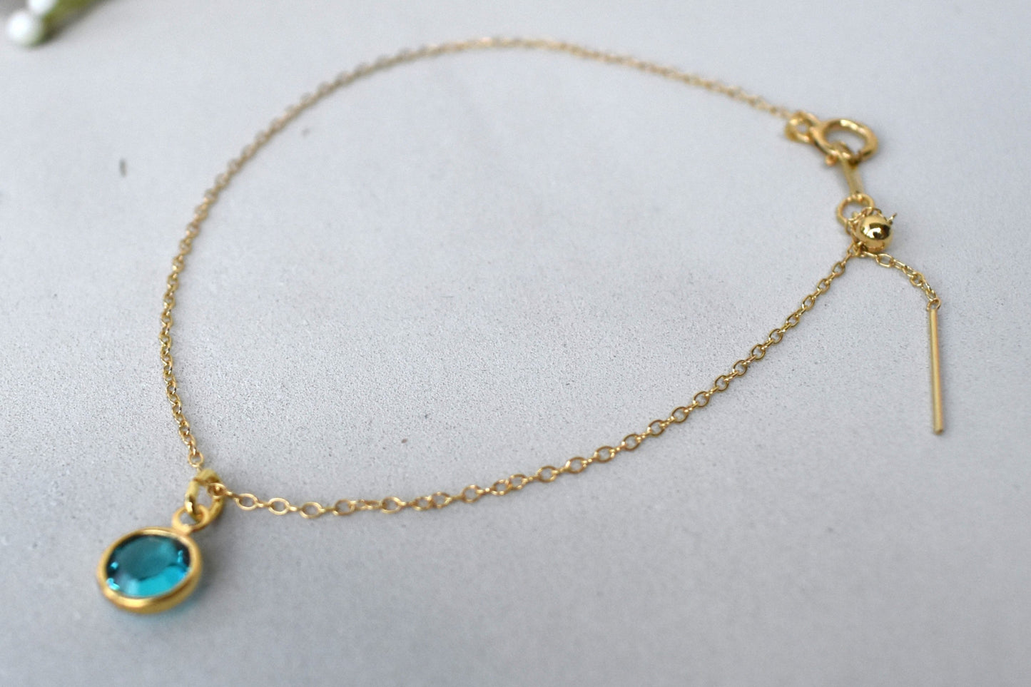 A gold filled chain is  threaded through a bead to make this delicate bracelet adjustable. Finished with a birthstone of your choice, ths bracelet is the perfect summer accessory.
