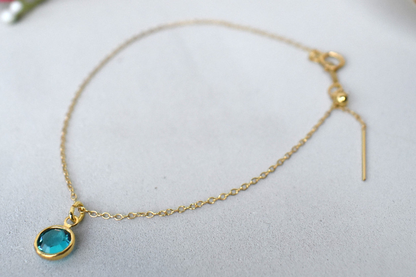 A gold filled chain is  threaded through a bead to make this delicate bracelet adjustable. Finished with a birthstone of your choice, ths bracelet is the perfect summer accessory.