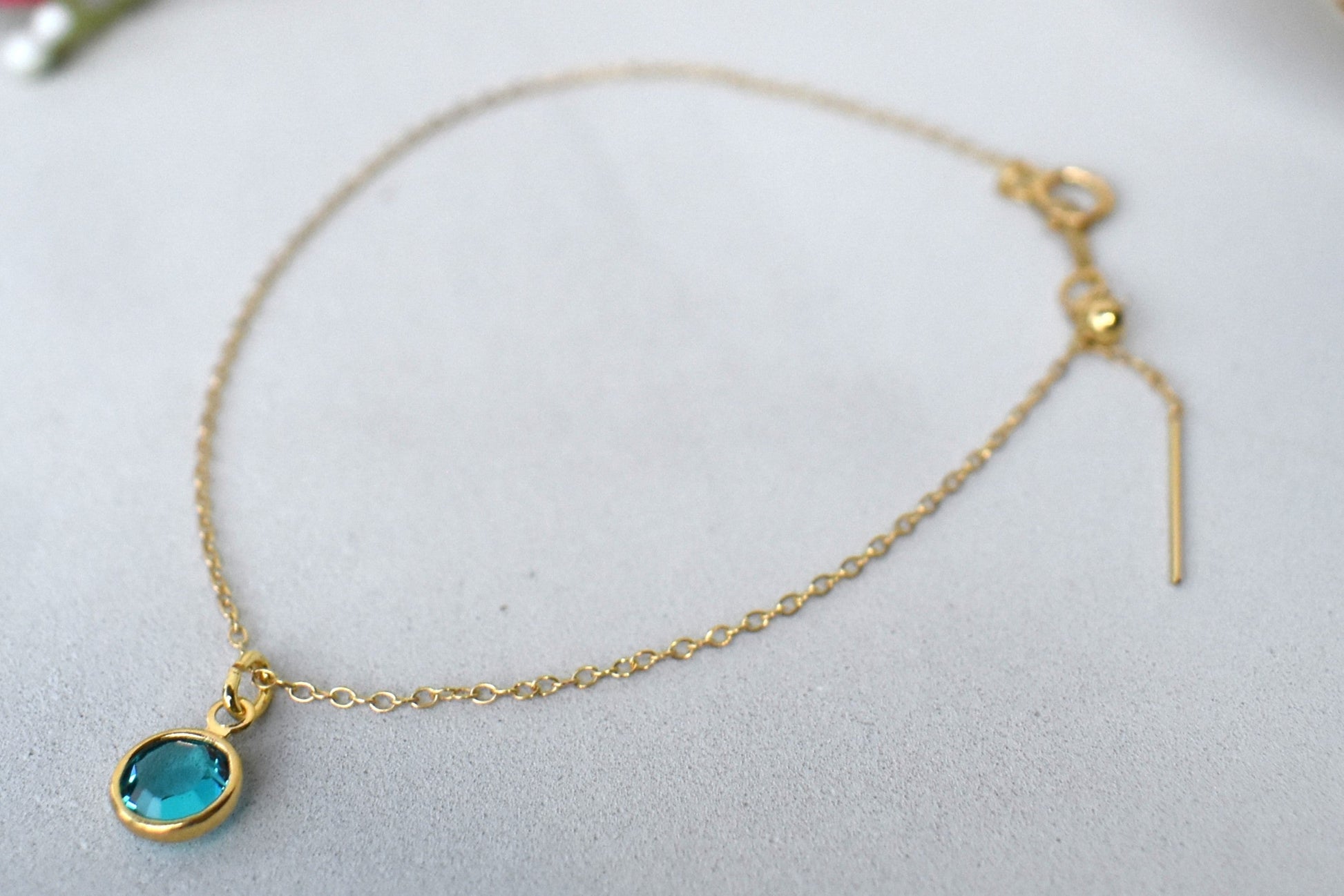 A gold filled chain is  threaded through a bead to make this delicate bracelet adjustable. Finished with a birthstone of your choice, ths bracelet is the perfect summer accessory.