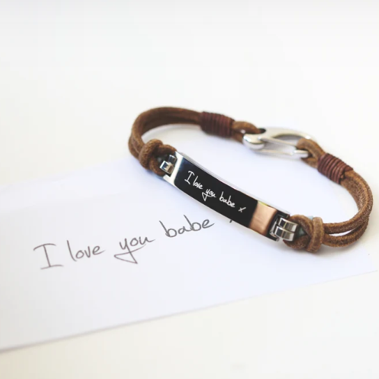 A brown leather bracelet with a central metal plate engraved with your own words and a silver lobster clasp