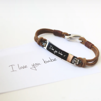 A brown leather bracelet with a central metal plate engraved with your own words and a silver lobster clasp
