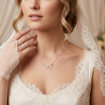 Bride wears a delicate sterling silver necklace of two hearts entwined together.