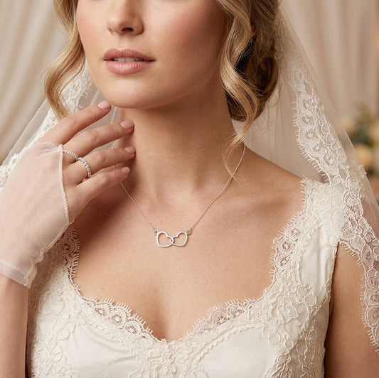 Bride wears a delicate sterling silver necklace of two hearts entwined together.