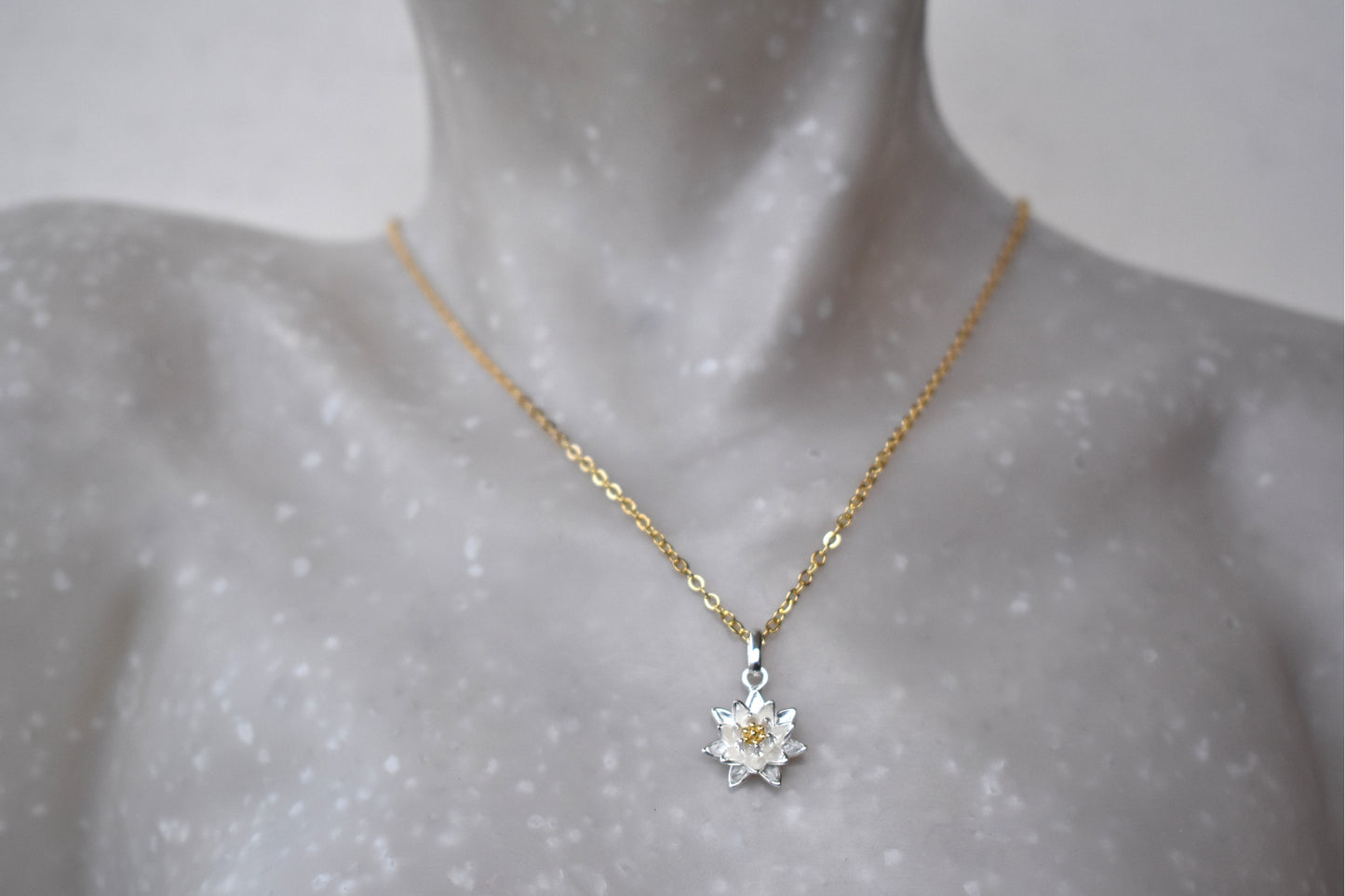 Gold Daisy Birth Flower necklace with a silver pendant on a mannequin