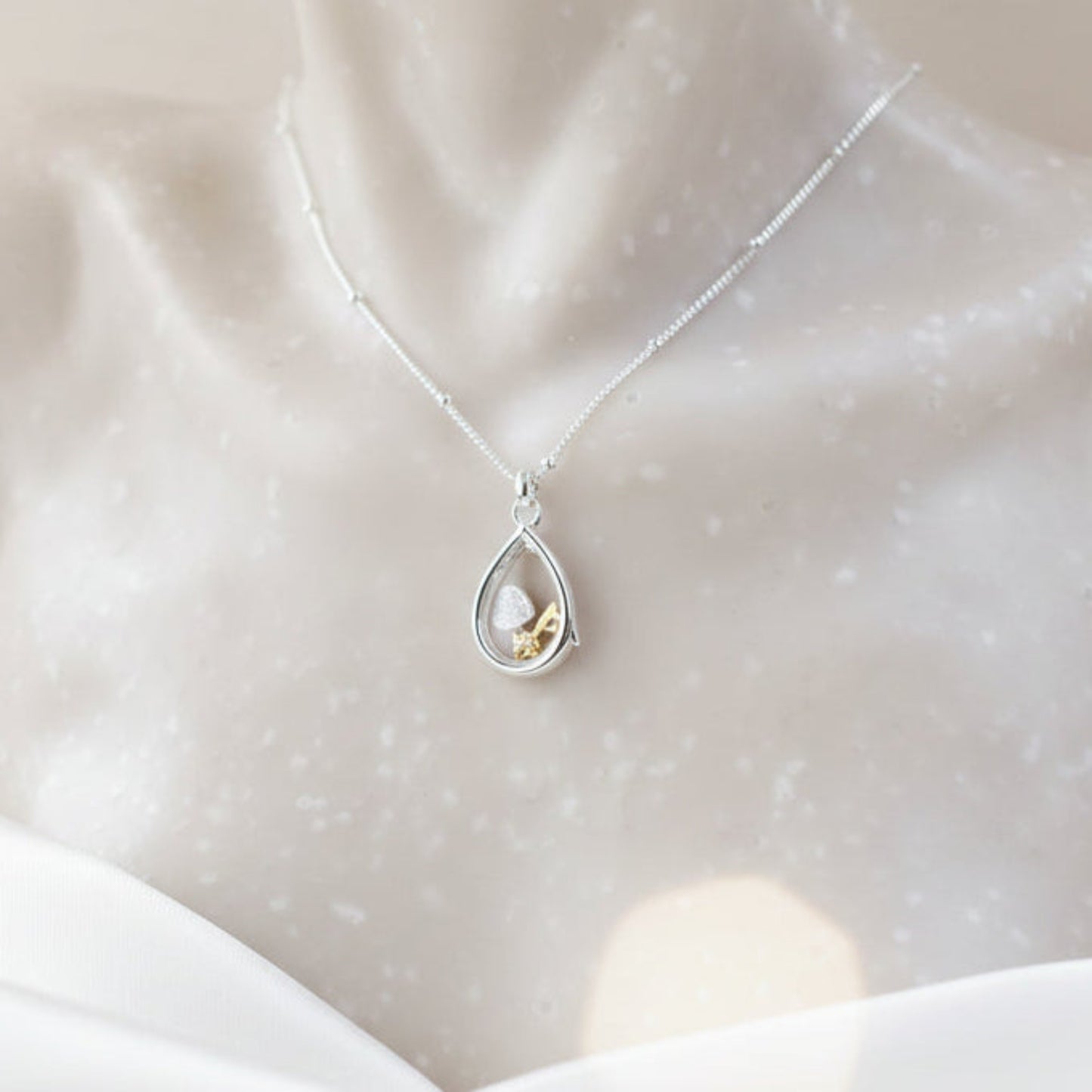 Sterling silver pear-shaped glass locket with tiny heart and key charms on a beaded chain