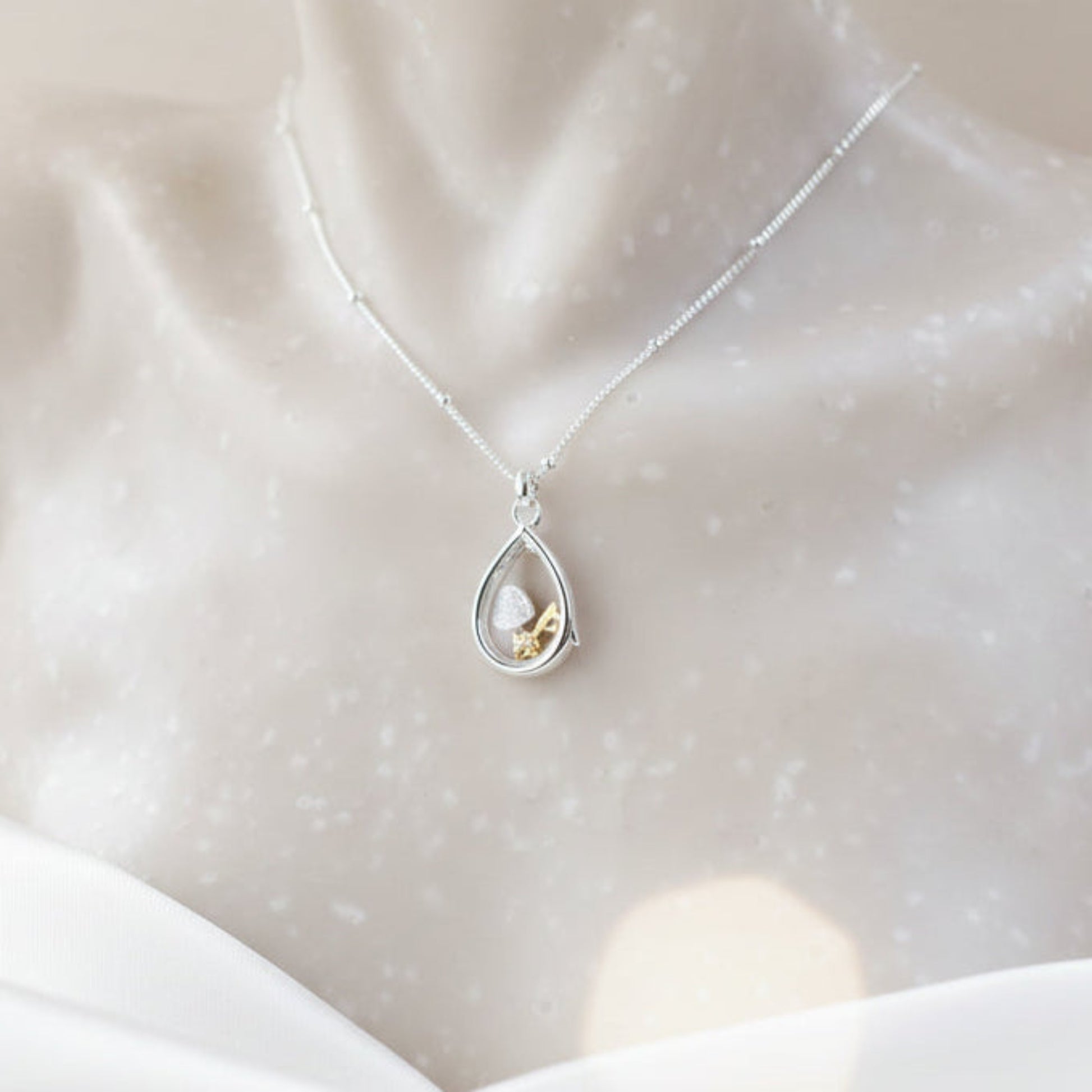 Sterling silver pear-shaped glass locket with tiny heart and key charms on a beaded chain
