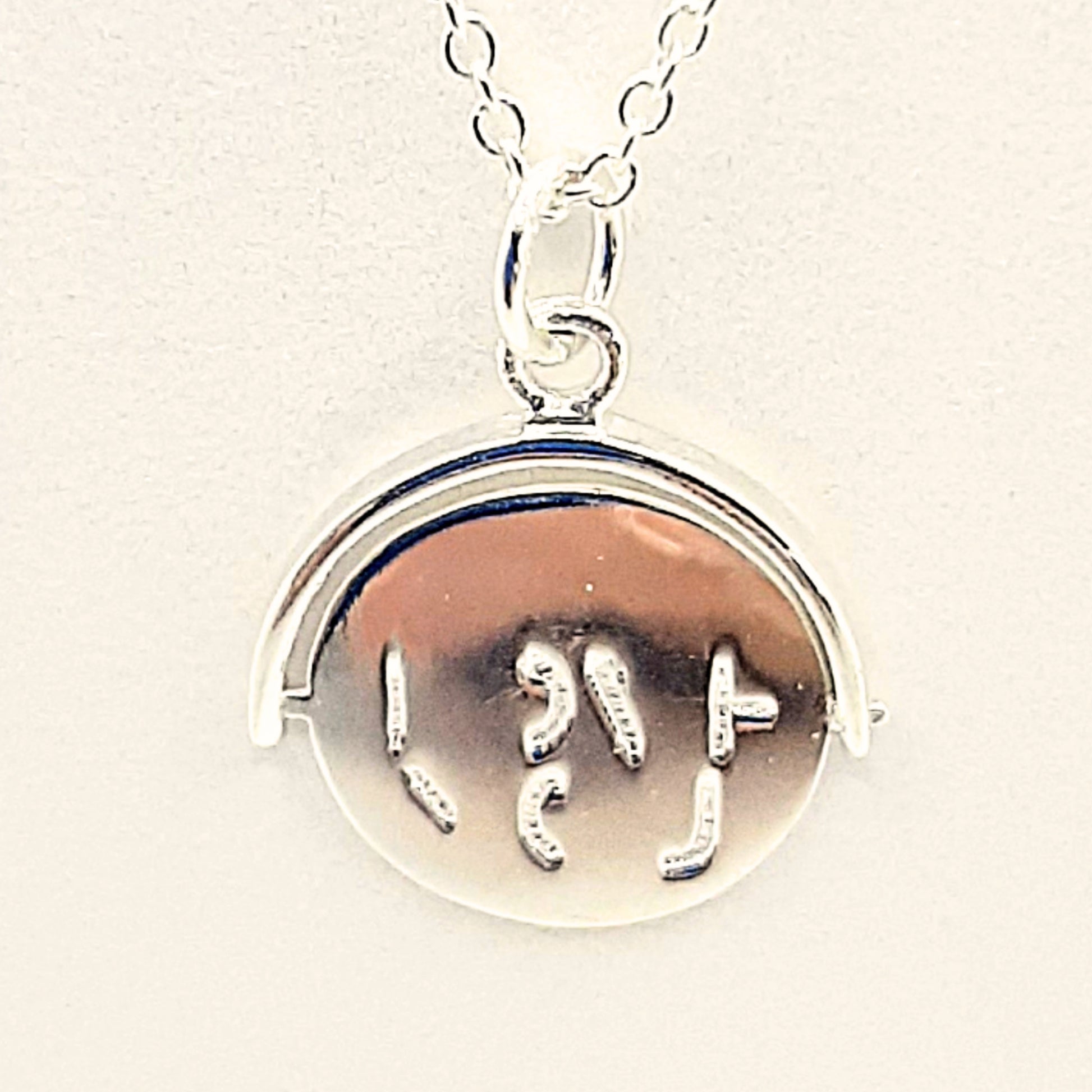 Sterling silver pendant with markings on both sides. When the disc is spun, it forms the words "I  LOVE YOU"