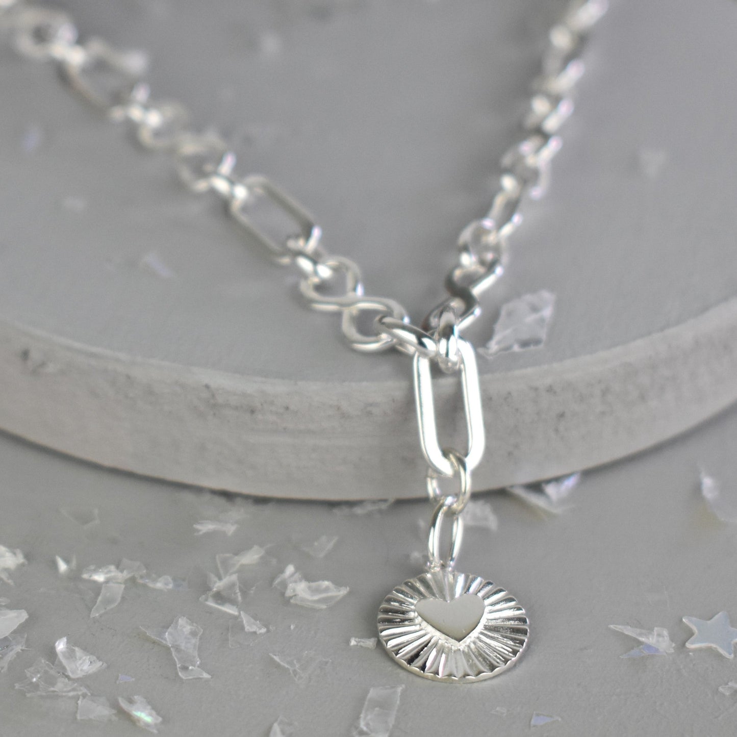 Sterling Silver Handmade Flat Link Infinity Necklace featuring a Heart Rays Pendant. Showcases flat oval and infinity links and features a Sterling Silver Sunburst Heart Rays charm pendant surrounded by an intricate sun rays design