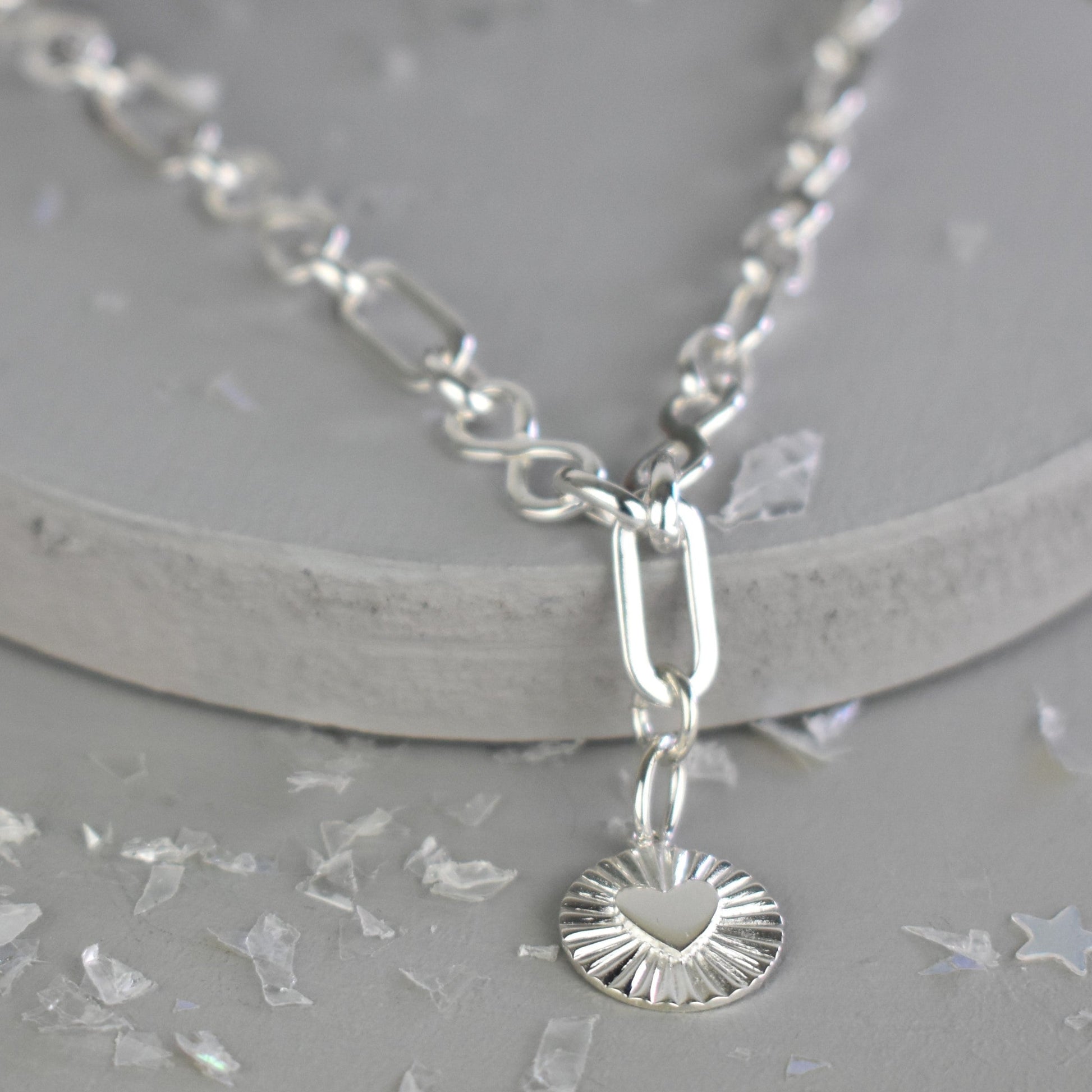 Sterling Silver Handmade Flat Link Infinity Necklace featuring a Heart Rays Pendant. Showcases flat oval and infinity links and features a Sterling Silver Sunburst Heart Rays charm pendant surrounded by an intricate sun rays design