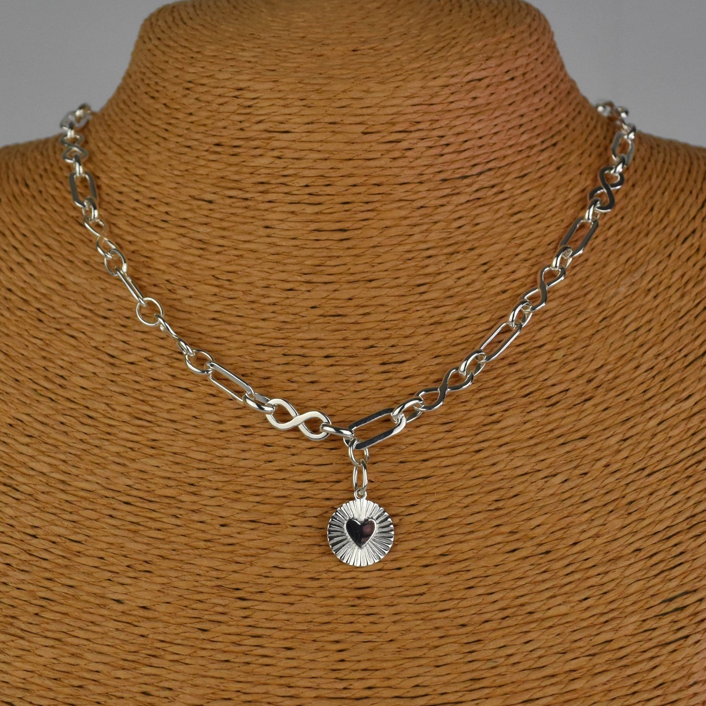 Sterling Silver Handmade Flat Link Infinity Necklace featuring a Heart Rays Pendant. Showcases flat oval and infinity links and features a Sterling Silver Sunburst Heart Rays charm pendant surrounded by an intricate sun rays design