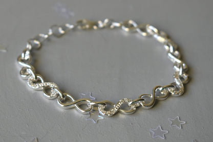 Sterling silver Infinity link bracelet with cubic zirconia inlays. Adjustable.