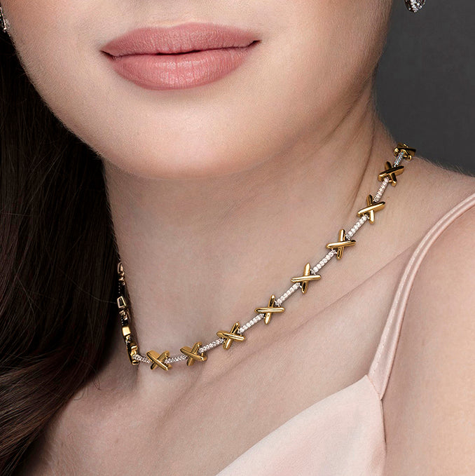 Model wears a delicate sterling silver necklace with gold plated kiss charms separated by sparkling CZ stones. Comes with small extension chain