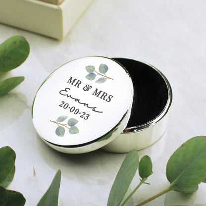 A round silver colour ring box with tiny leaves and an inscript of Mr & Mrs, surname and the wedding date