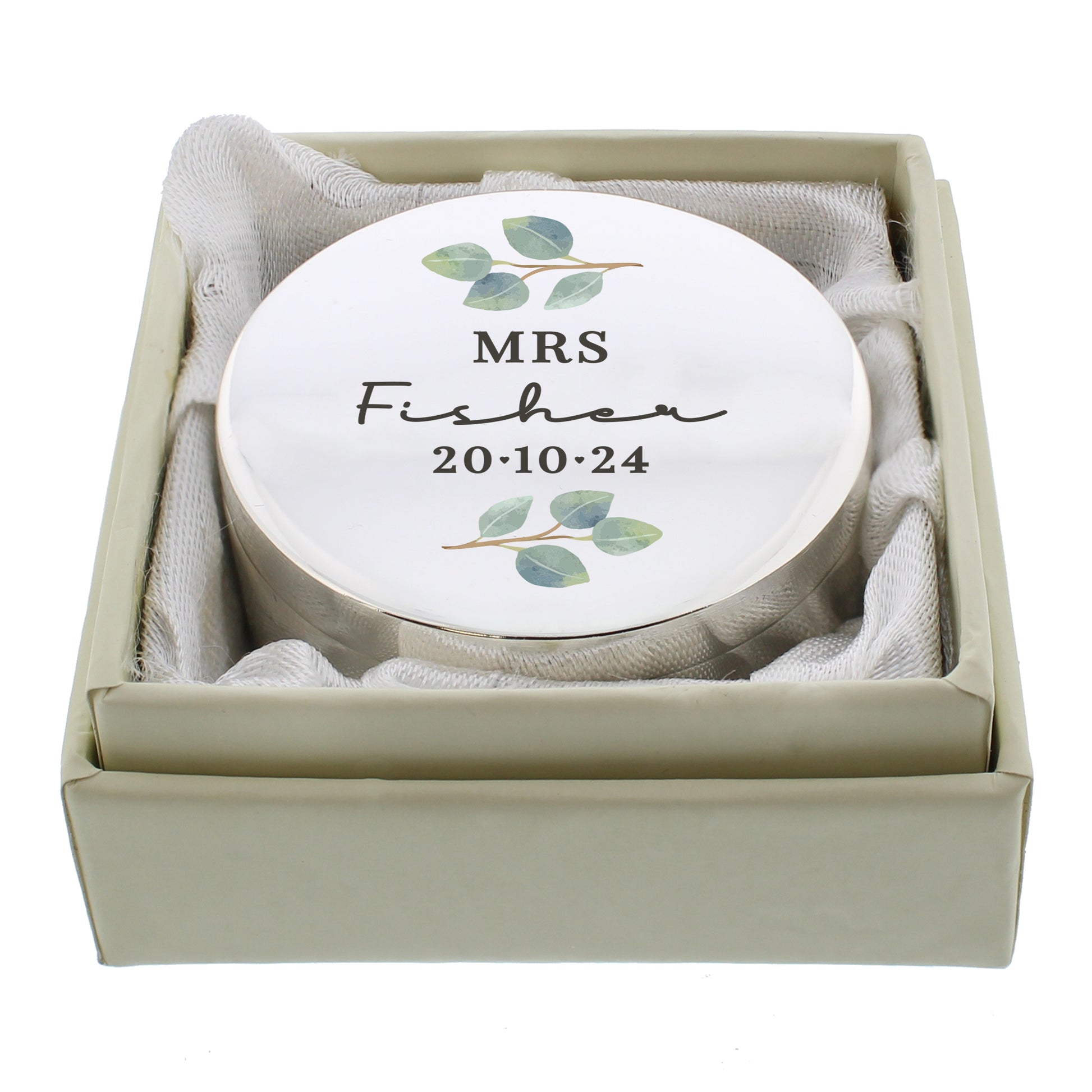 A round silver colour ring box with tiny leaves and an inscript of Mr & Mrs, surname and the wedding date. Shown in accompanying gift box.
