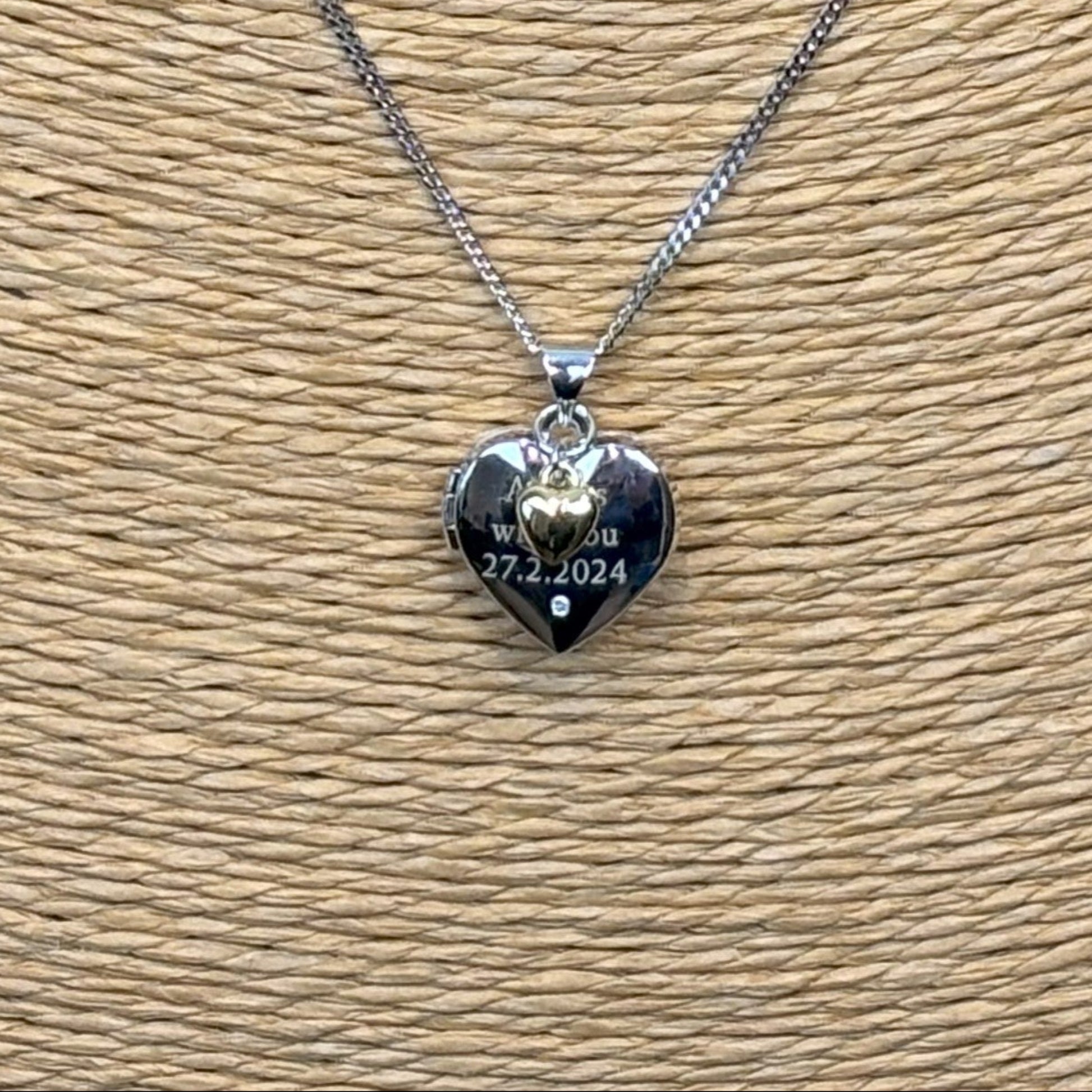 sterling silver heart shaped locket with engraved message and tiny gold heart, close up view