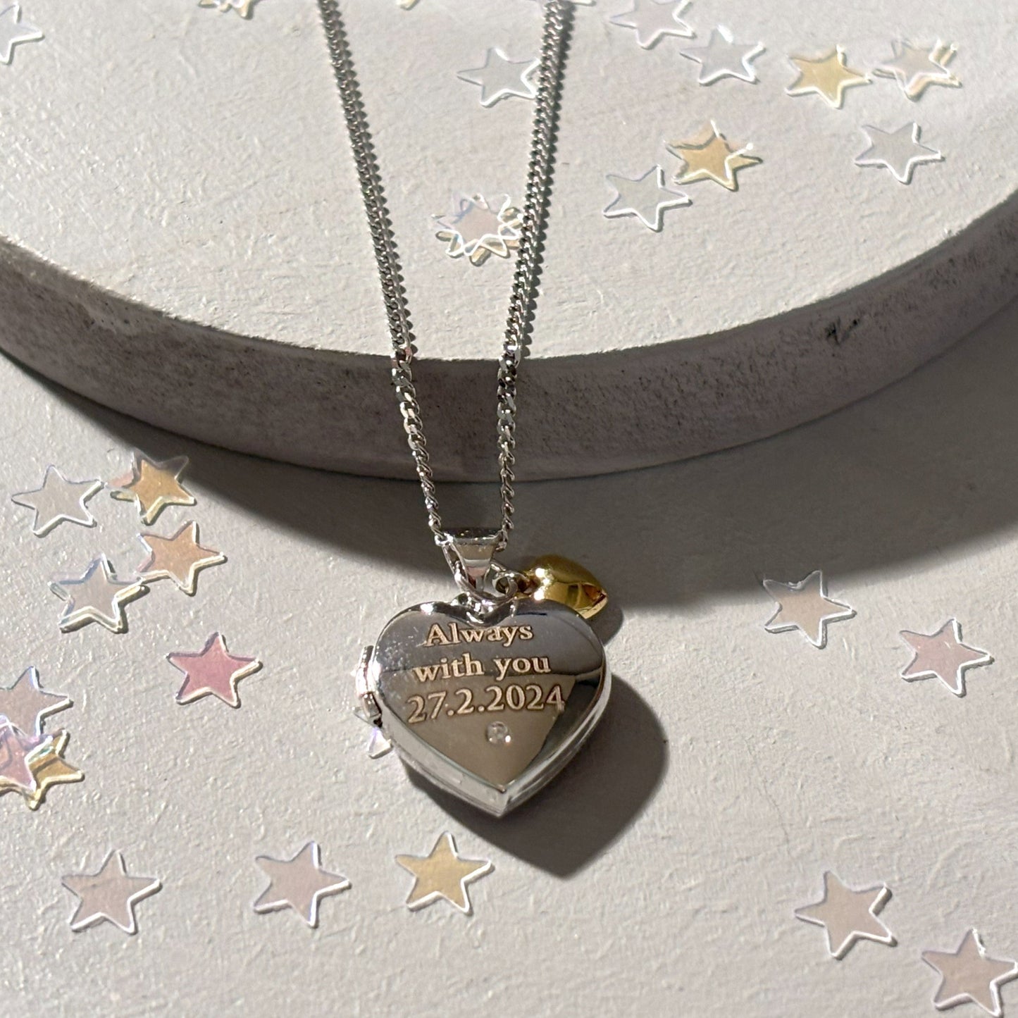 sterling silver heart shaped locket with engraved message and tiny gold heart, close up view