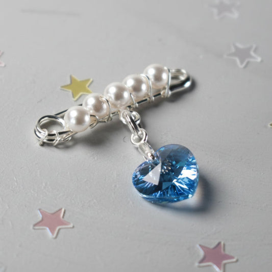 A sterling silver safety pin is finished with 4mm white glass pearls The loop on the pin hold a sterling silver bail with the highest quality blue crystal heart. The pin can be pinned to a wedding bouquet or worn inside the wedding gown as a secret something blue.