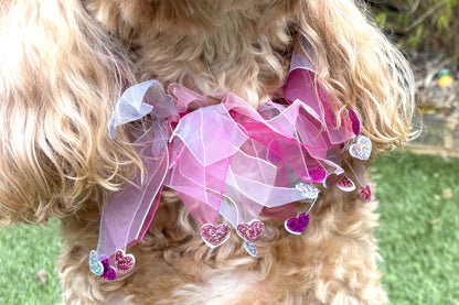Elasticated love heart frill collar adds a touch of charm to your dog's look. Made from high-quality materials, this playful collar features a stylish love heart design and a decorative frill made of white and pink tulle ribbons. One size shown on Cockapoo model. Worn on its own or easily slipped on top of collar
