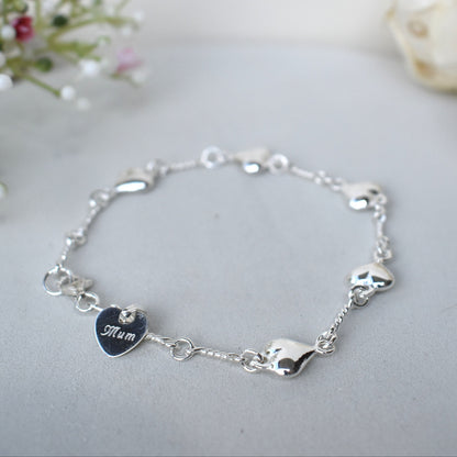 Sterling silver puffed hearts linked together by long twisted links. Next to the fastener is a small 10mm sterling silver heart engraved with a name of our choice.