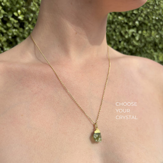Gold necklace with a raw crystal pendant worn by model