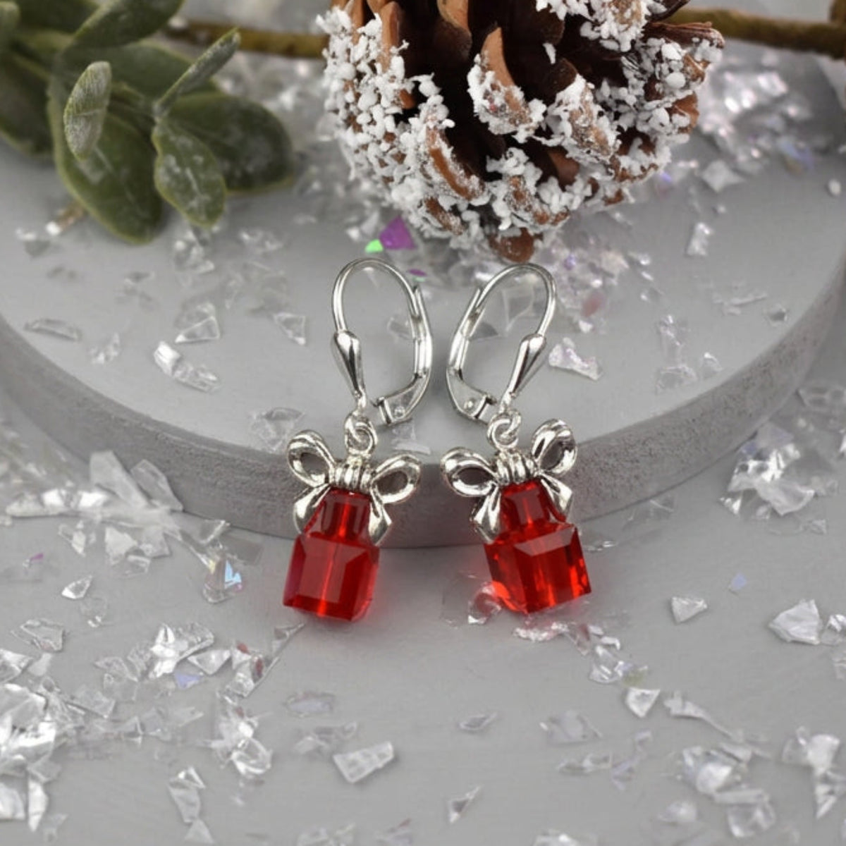 A pair of red Austrian Crystal Christmas parcel earrings topped with a bow and fastened onto sterling silver leverback wires.