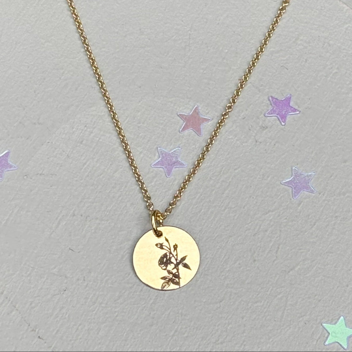 delicate Gold Filled Birth Flower Pendant. Crafted on an 11mm coin pendant, this simple piece is engraved with the intricate design of birth flowers on the front side and on the reverse side features a hidden personalised engraving, making it truly unique.