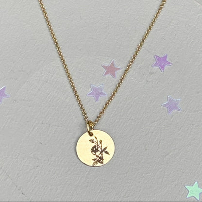 delicate Gold Filled Birth Flower Pendant. Crafted on an 11mm coin pendant, this simple piece is engraved with the intricate design of birth flowers on the front side and on the reverse side features a hidden personalised engraving, making it truly unique.