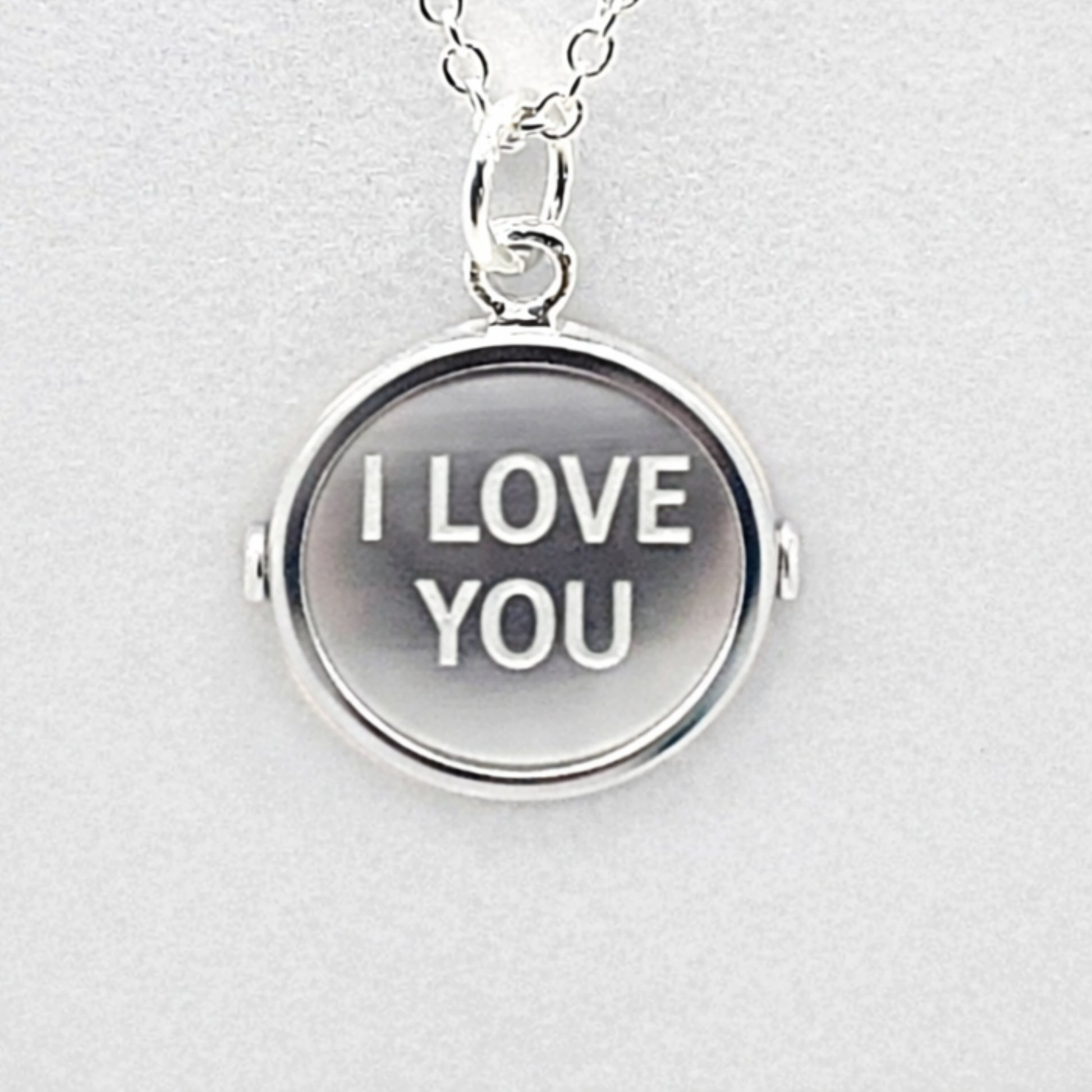 Simulated view of sterlnng silver pendant with markings on both sides that, when spun, form the words "I LOVE YOU"