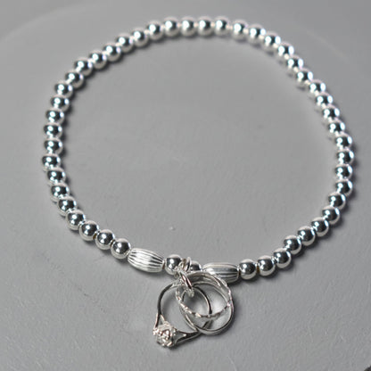 4mm sterling silver beads make this elasticated bracelet finished with three rings symbolising engagement, wedding and eternity rings
