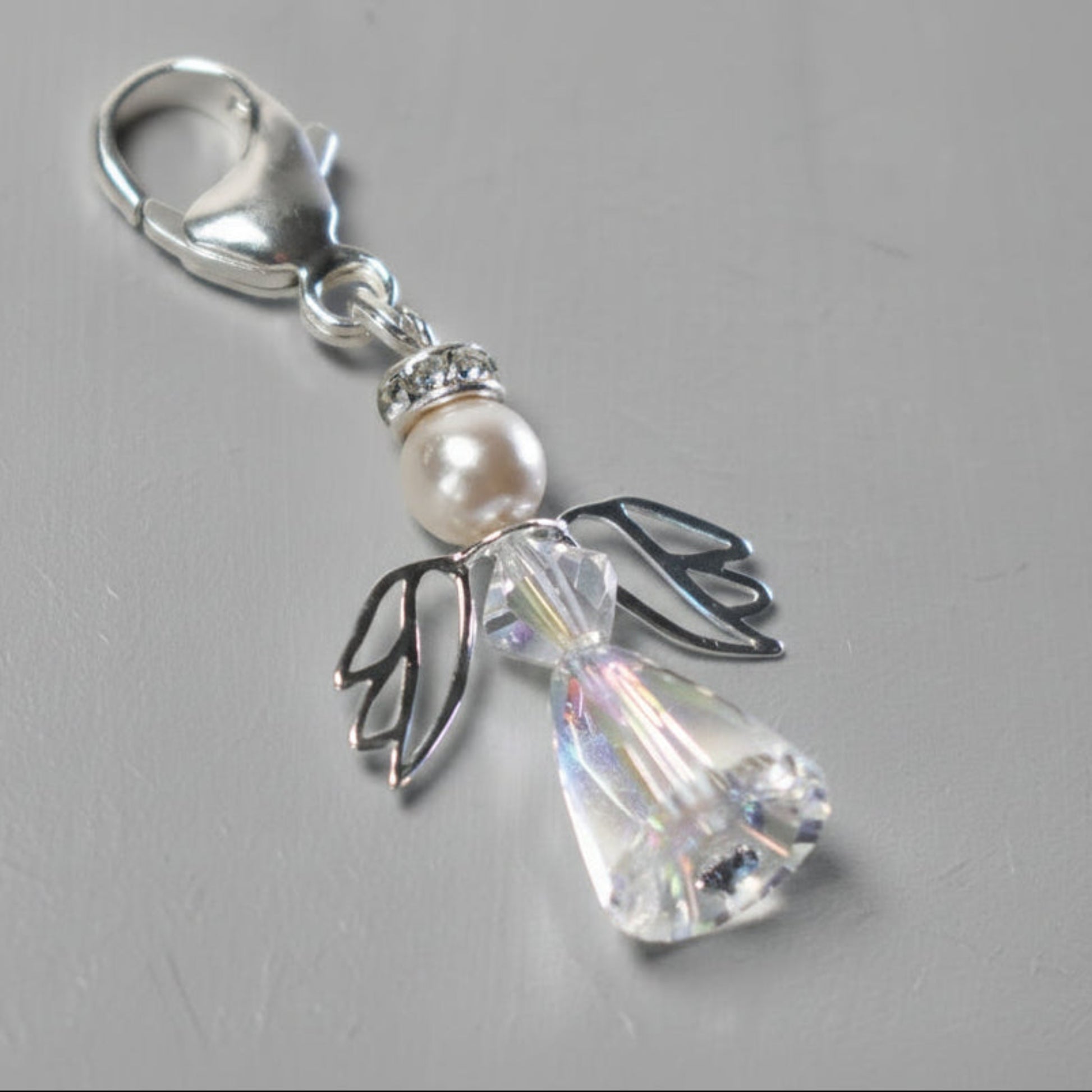 A crystal and pearl angel on a sterling silver caribiner. Ideal for bouquets, on a handbag or as a key charm. Shown with a tiny blue crystal at base, although this can be exchange for an alternative colour if preferred.