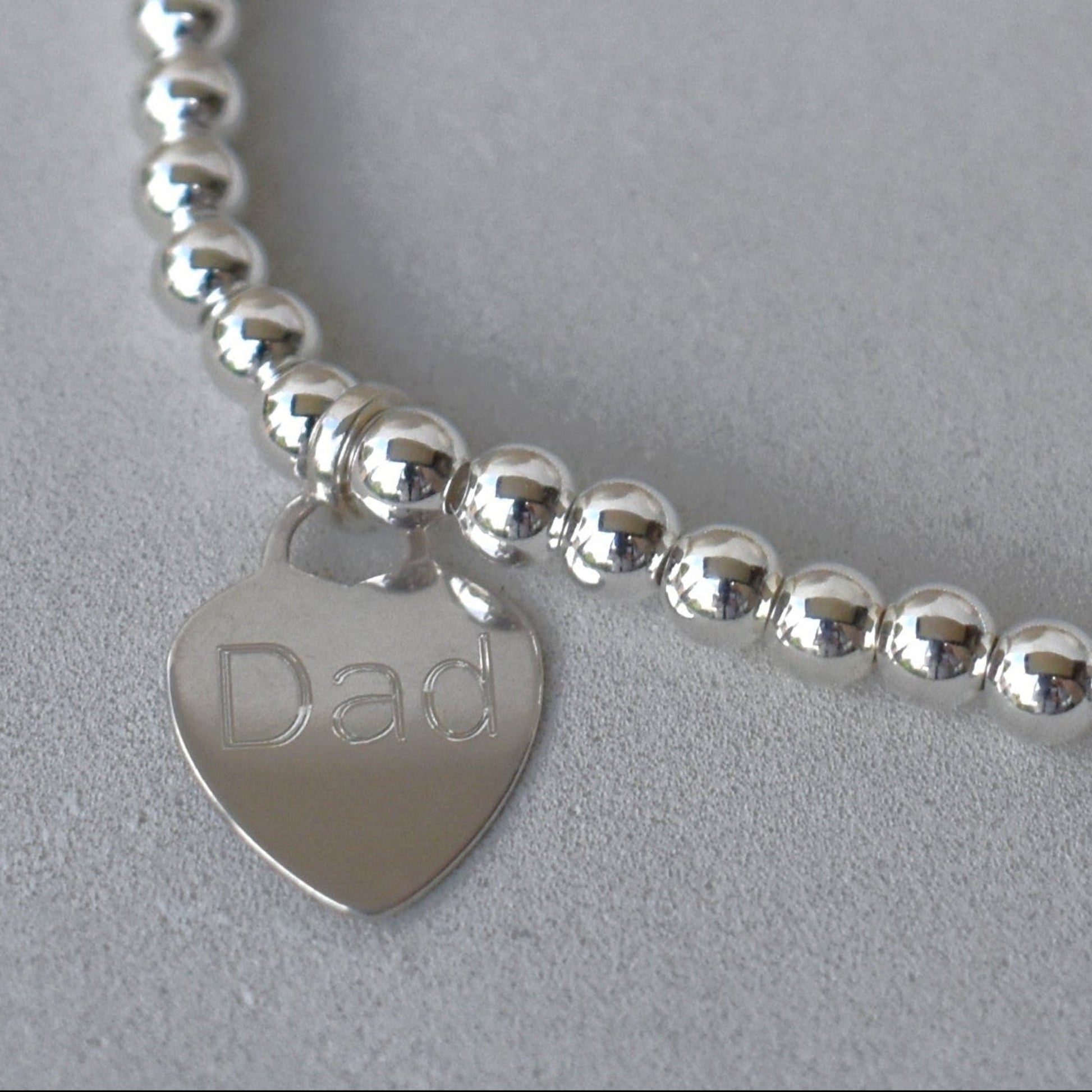 Close up of engraved sterling silver heart charm, custom name or date, sterling silver shown