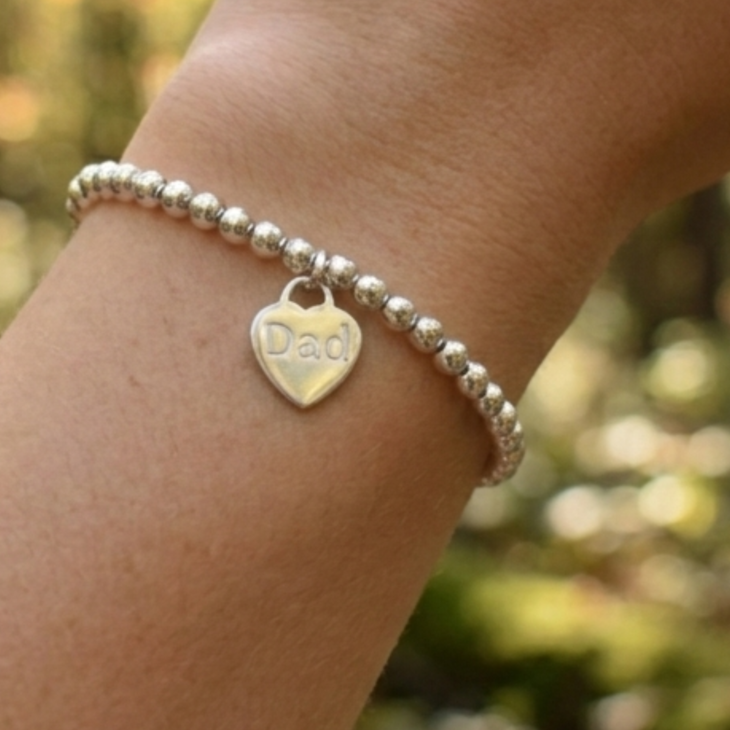 Sterling silver 4mm beaded bracelet with a 16mm sterling silver heart engraved with the word "Dad". Engraving can be words of your choice. Bracelet is threaded onto strong elastic, no fastening required.