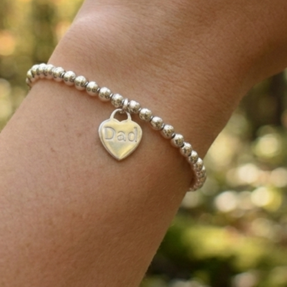 Sterling silver 4mm beaded bracelet with a 16mm sterling silver heart engraved with the word "Dad". Engraving can be words of your choice. Bracelet is threaded onto strong elastic, no fastening required.