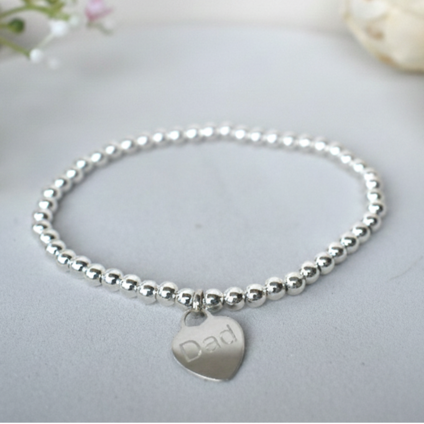 Silver beaded bracelet  of 4mm sterling silver beads threaded on strong elastic with a suspended sterling silver heart that can be engraved with wording of your choice. 