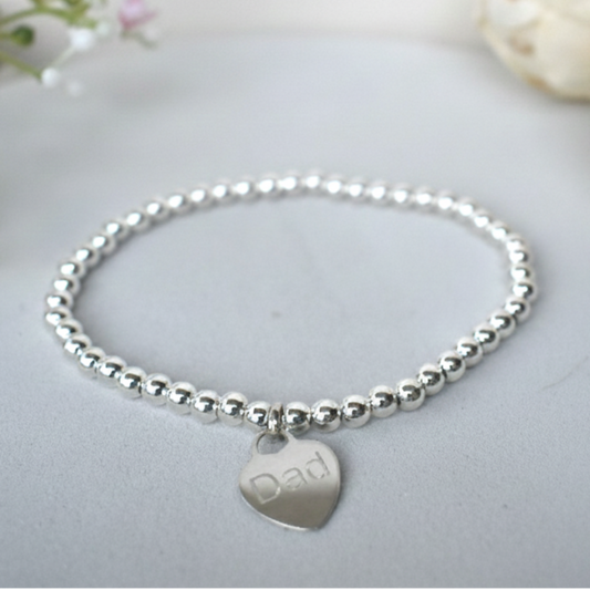 Silver beaded bracelet  of 4mm sterling silver beads threaded on strong elastic with a suspended sterling silver heart that can be engraved with wording of your choice. 