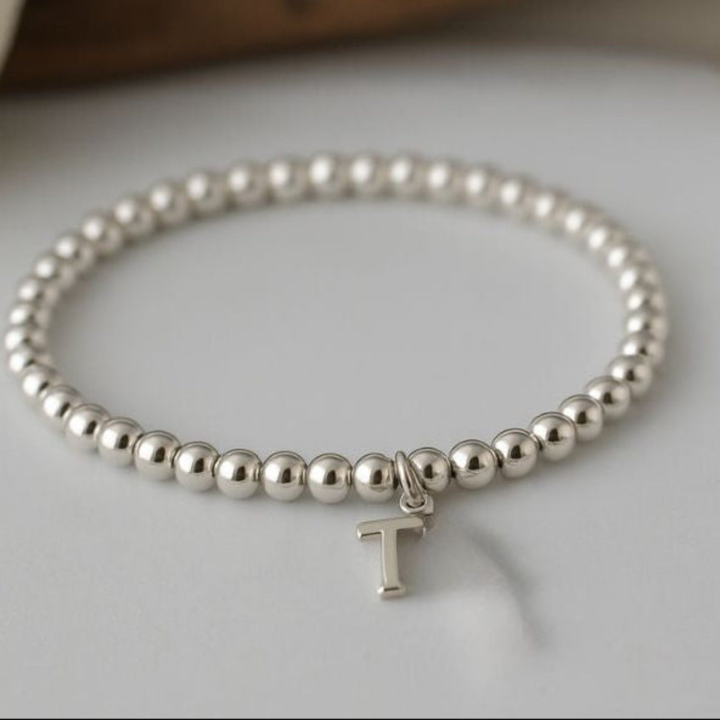 A beaded bracelet shown with the design of the optional sterling silver initial charm