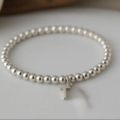 A beaded bracelet shown with the design of the optional sterling silver initial charm