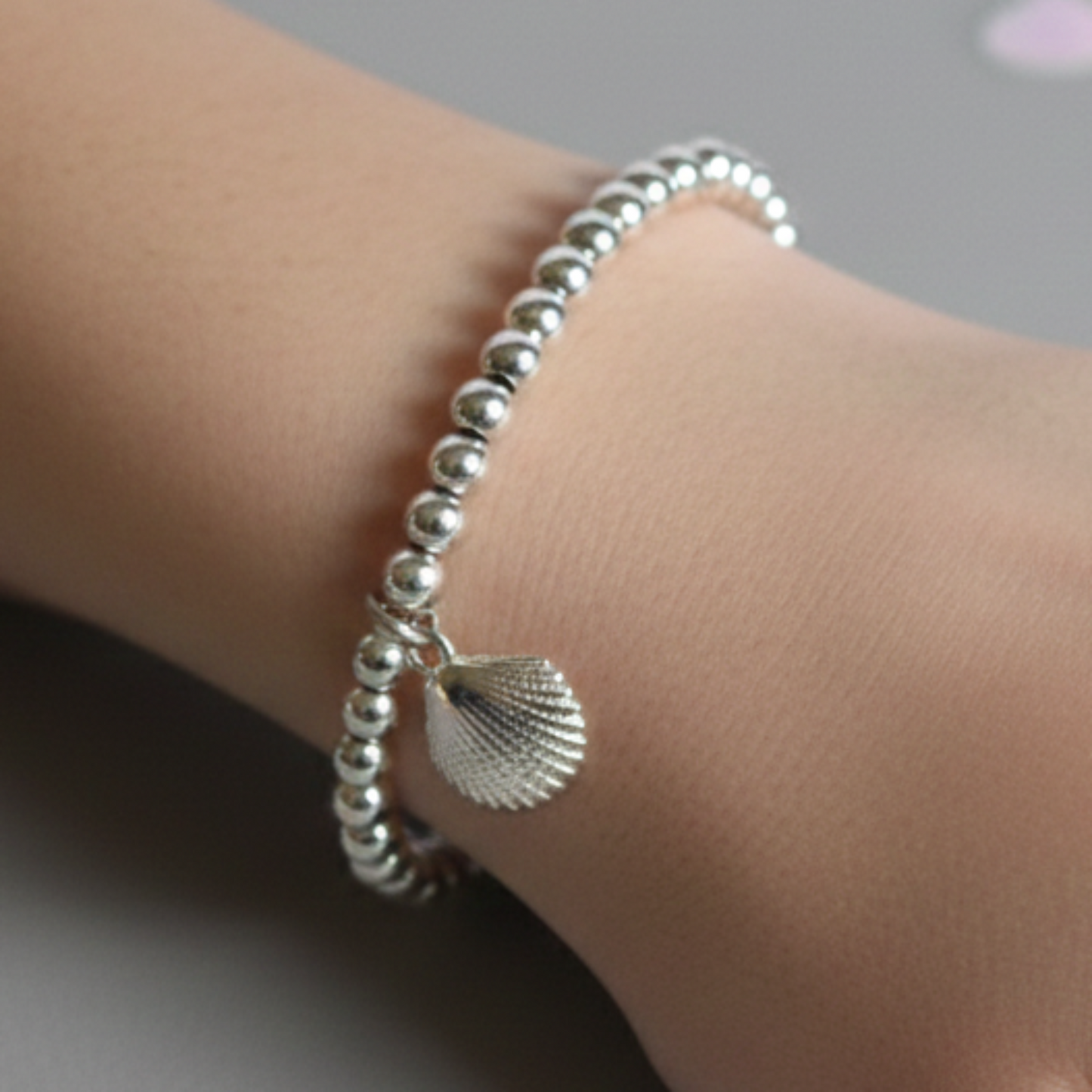 Sterling silver beaded bracelets with 4mm beads. Suspended from the bracelet  is a sterling silver clamshell.  Shown worn