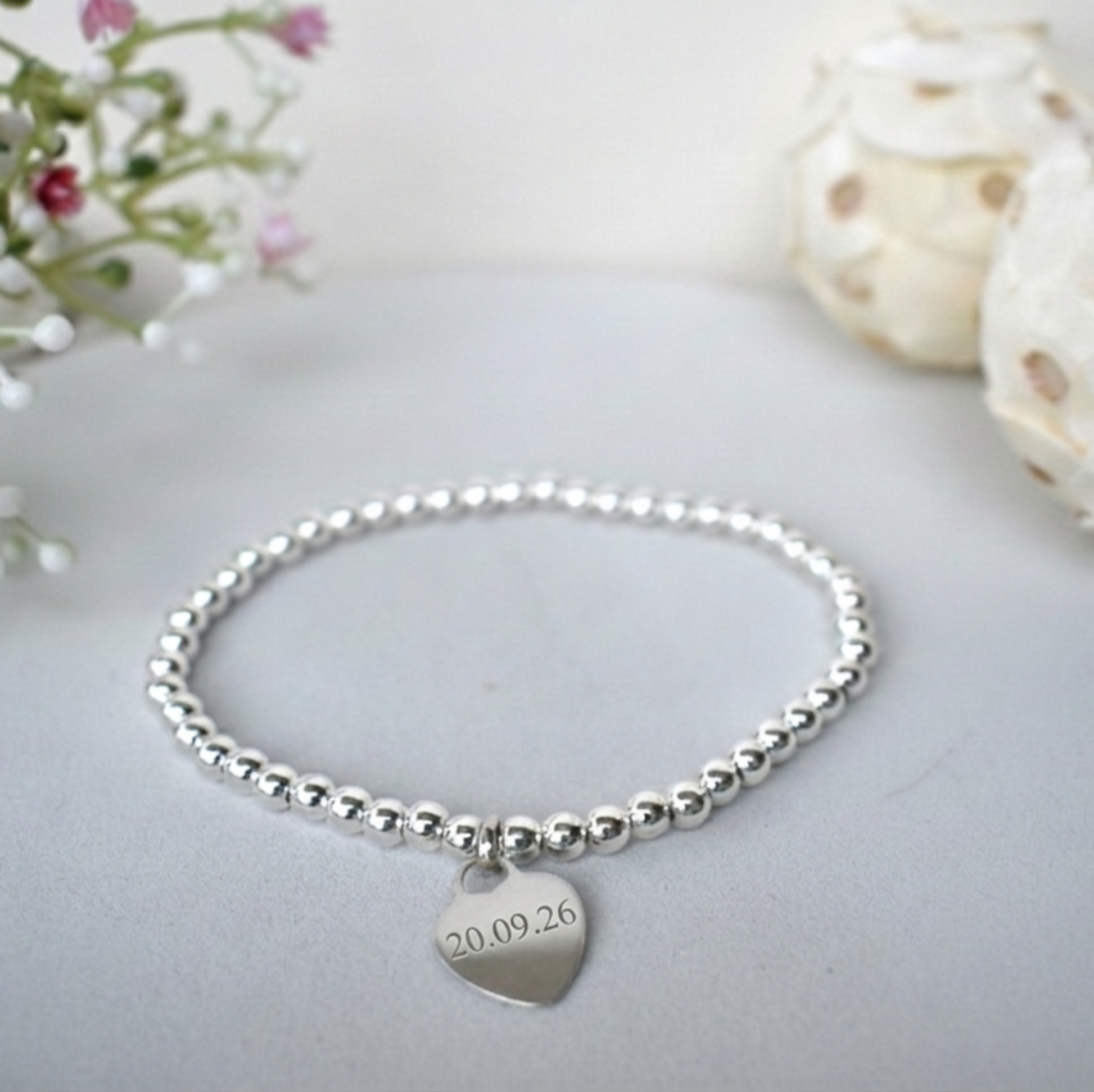 A sterling silver elasticated beaded bracelet carrying sterling silver  heart  engraved with a special date
