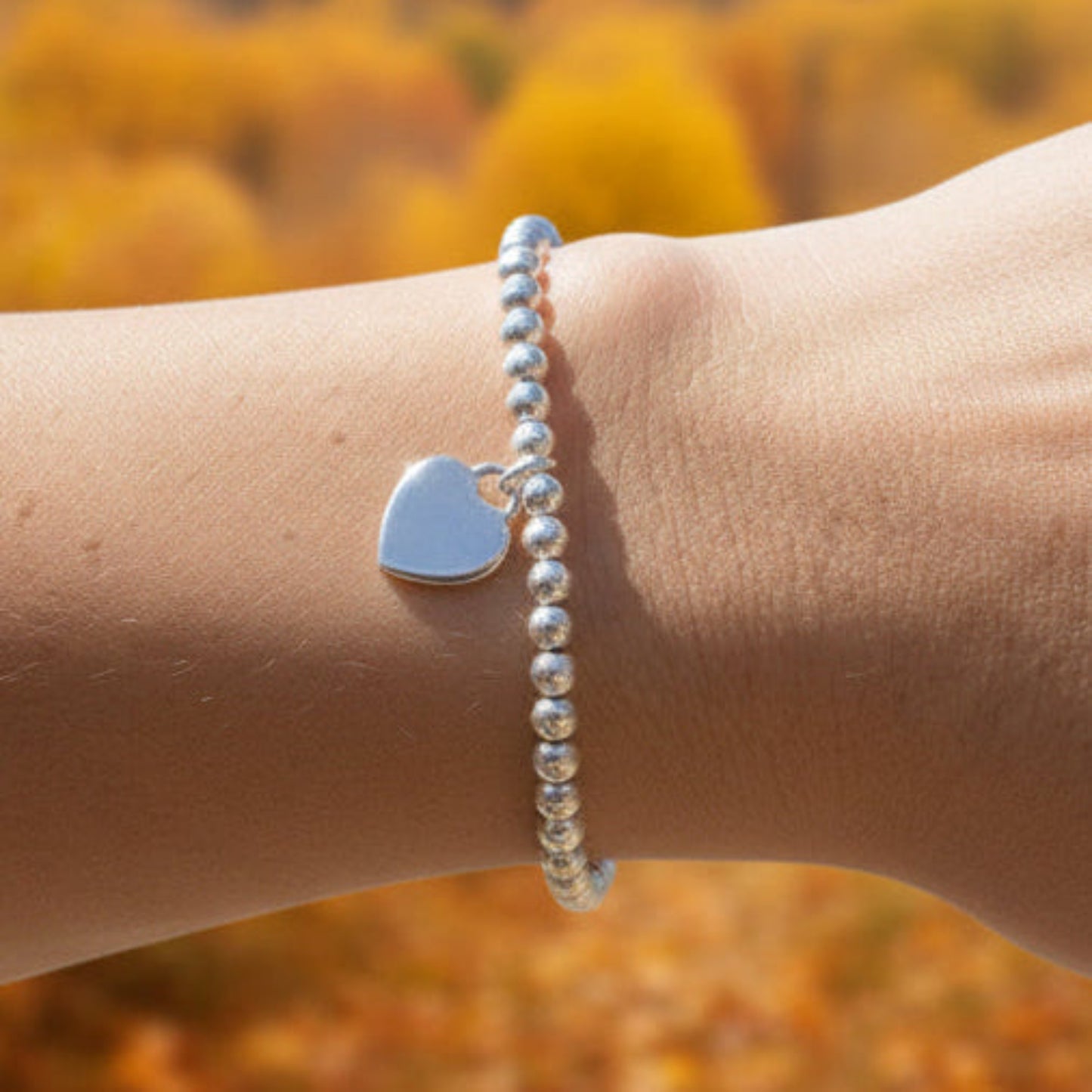 16mm heart shaped sterling silver locket suspended from 4mm sterling silver beads threaded onto strong elastic. The locket opens for you to add two photos of your choice. Shown worn