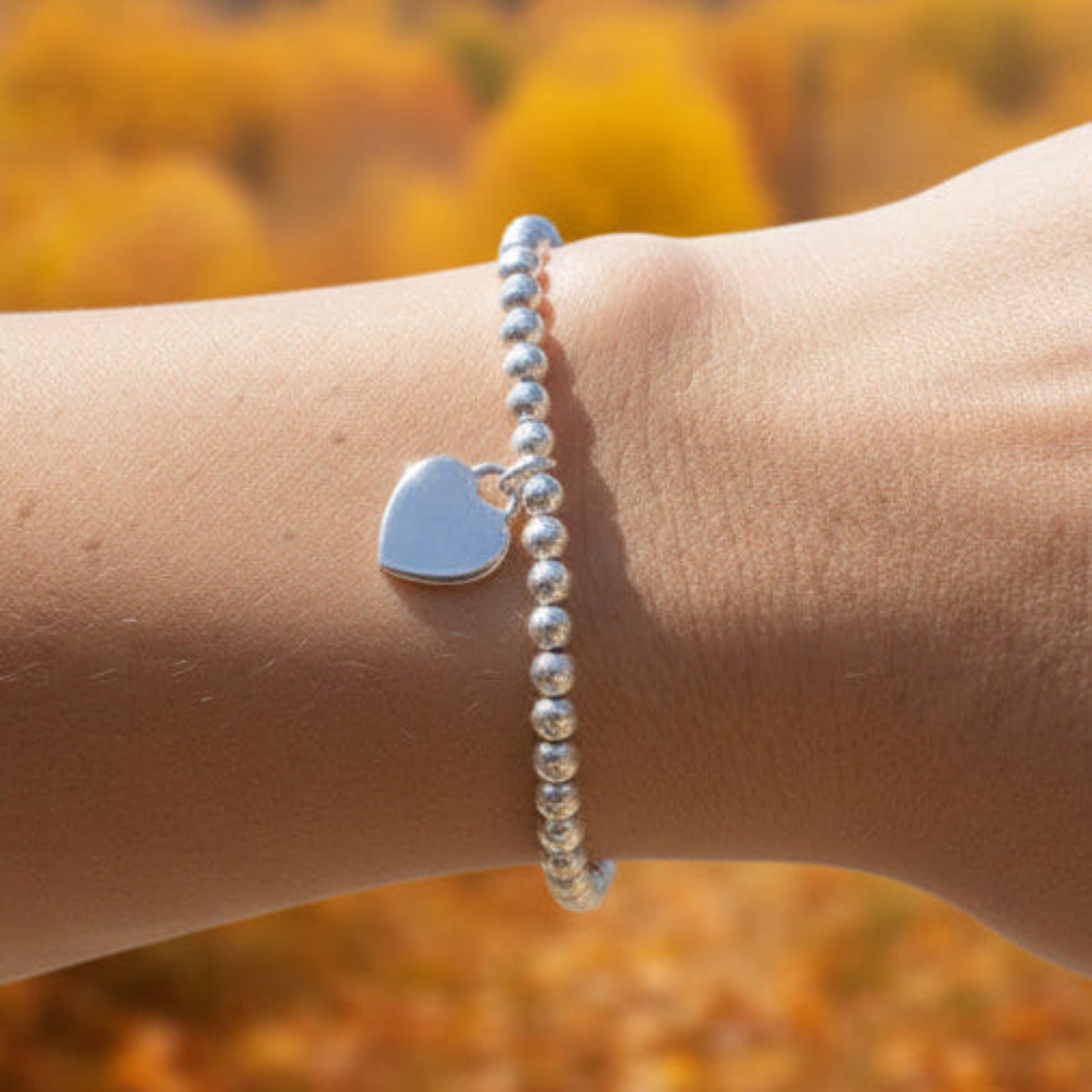 16mm heart shaped sterling silver locket suspended from 4mm sterling silver beads threaded onto strong elastic. The locket opens for you to add two photos of your choice. Shown worn