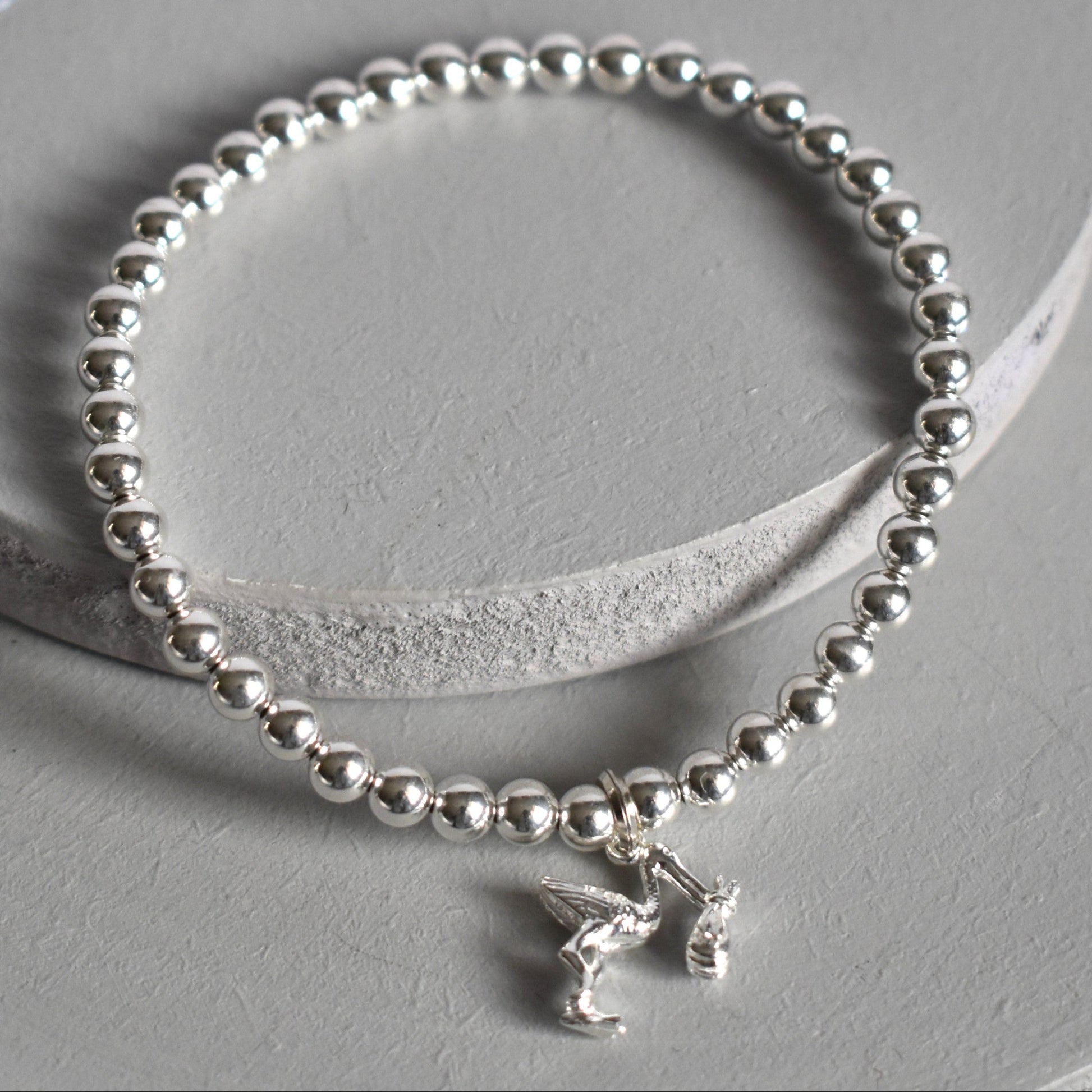 4mm sterling silver beads are threaded onto strong elastic from which is suspended a sterling silver stork carrying a little bundle. The perfect bracelet for new mums.