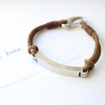 A brown leather bracelet with a central metal plate engraved with your own words and a silver lobster clasp
