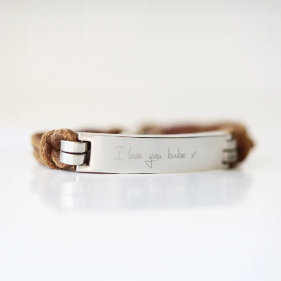A brown leather bracelet with a central metal plate engraved with your own words and a silver lobster clasp